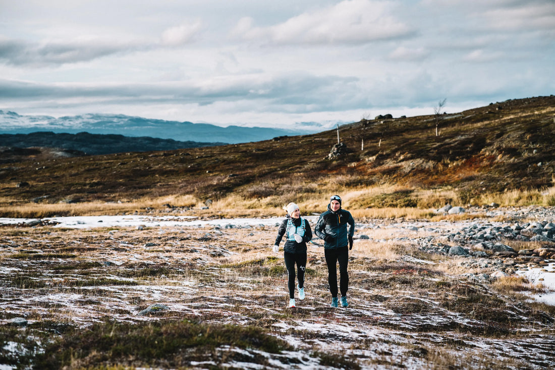 To personer jogger sammen over fjellvidda på en kald senhøstdag med rim og snø på bakken